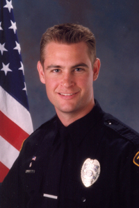 officer Bentley in TPD uniform with American flag behind him