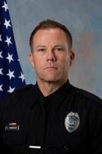 Sergeant Don Jorgensen headshot in TPD uniform next to American flag