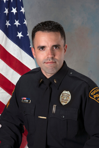 Captain Flores head shot in TPD uniform next to American flag