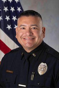 Lieutenant Garza in TPD Uniform next to American flag