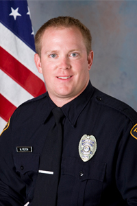 Officer Pelton in TPD uniform with American flag behind 