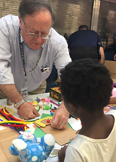TPD volunteer helps a child making a paper bag puppet